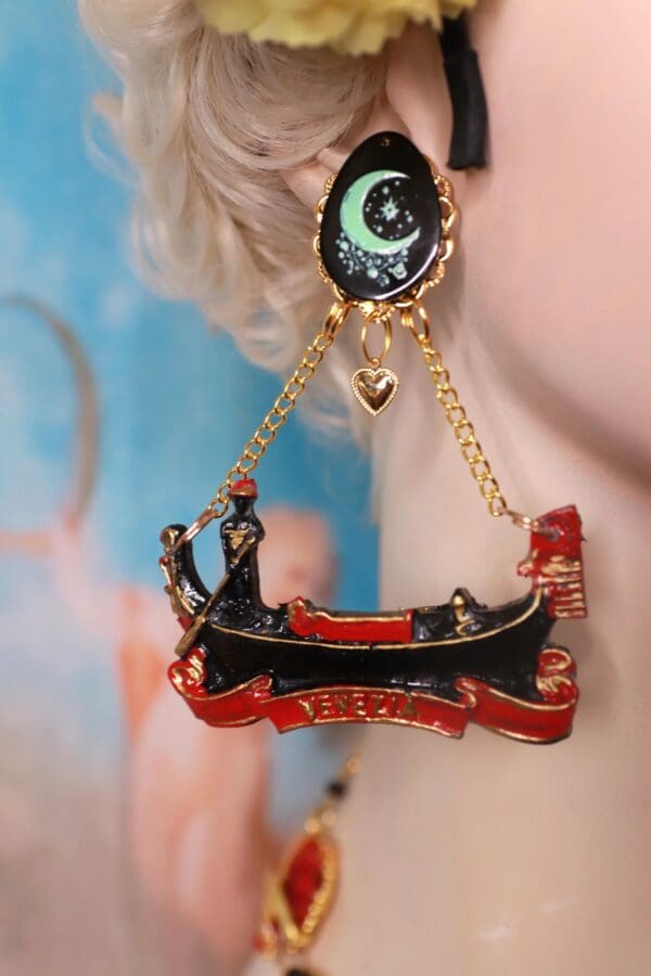 A woman wearing earrings with a boat and eye on them.
