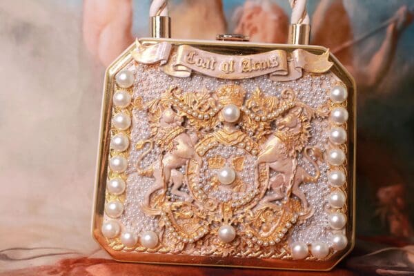 A gold purse with pearls and lace on top of it.