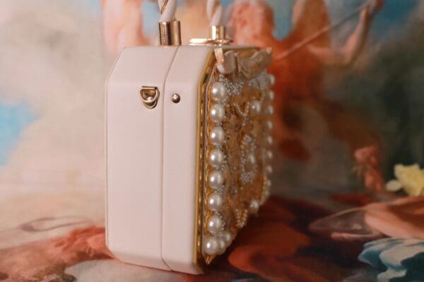 A white purse with pearls on top of it.