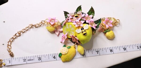 A close up of a necklace with lemons and flowers
