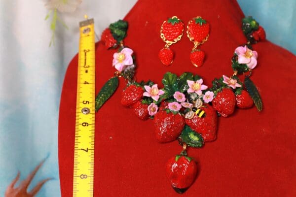 A red table with a strawberry necklace and earrings.