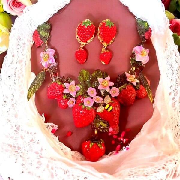 A close up of a necklace and earrings with strawberries