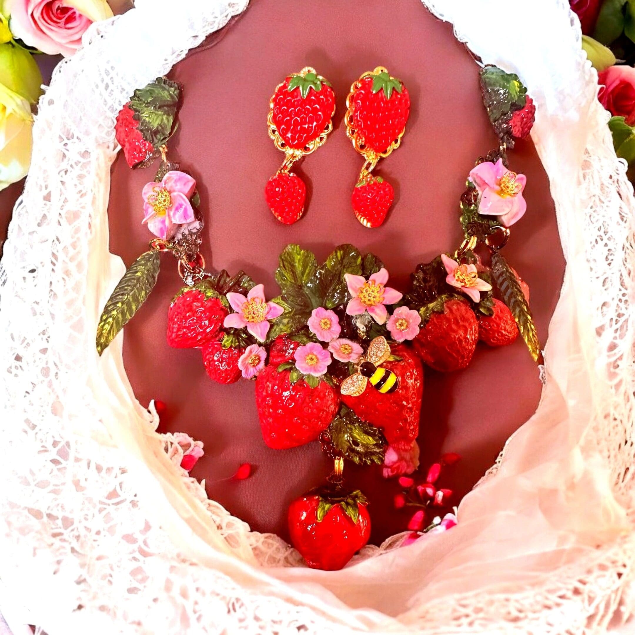 A close up of a necklace and earrings with strawberries