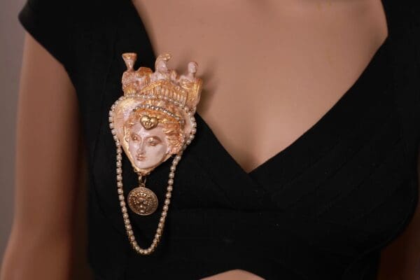 A woman wearing a black dress with pearls around her neck.