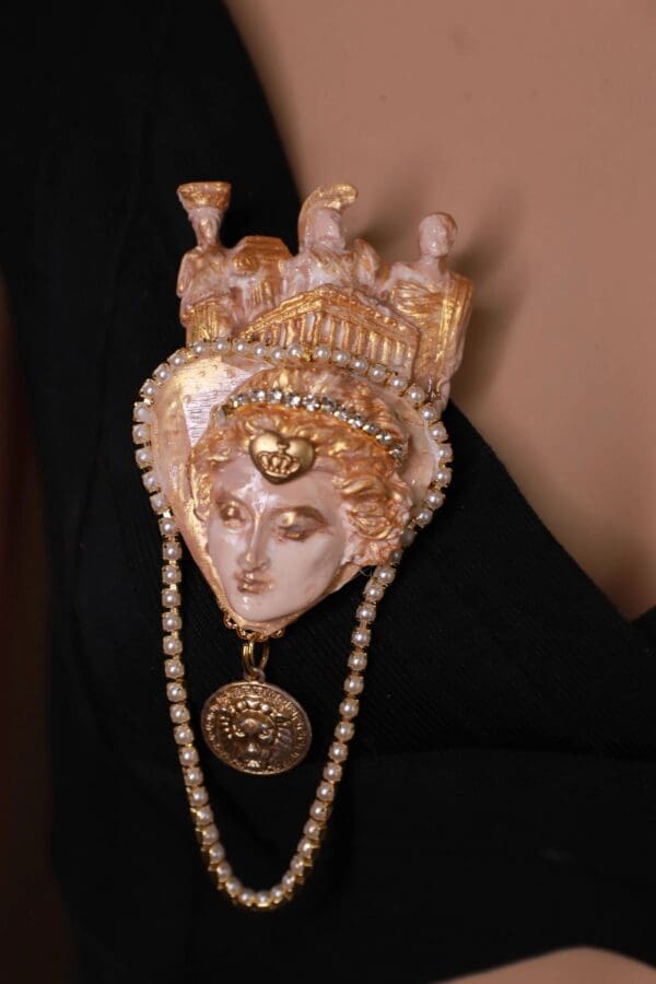 A white and gold mask with pearls hanging from it.