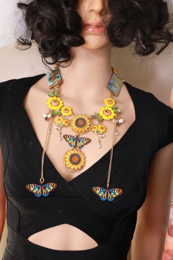 A woman wearing a necklace with sunflowers and butterflies.