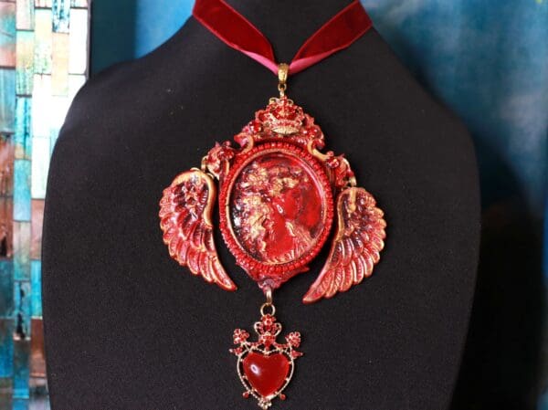 A red necklace with wings and hearts on it.