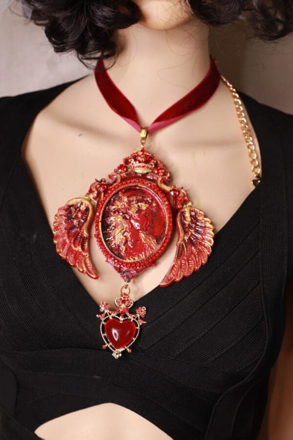 A woman wearing a red necklace with a heart shaped pendant.