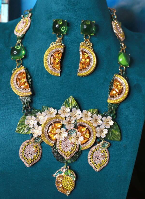 A necklace and earrings set with green leaves, flowers and orange slices.