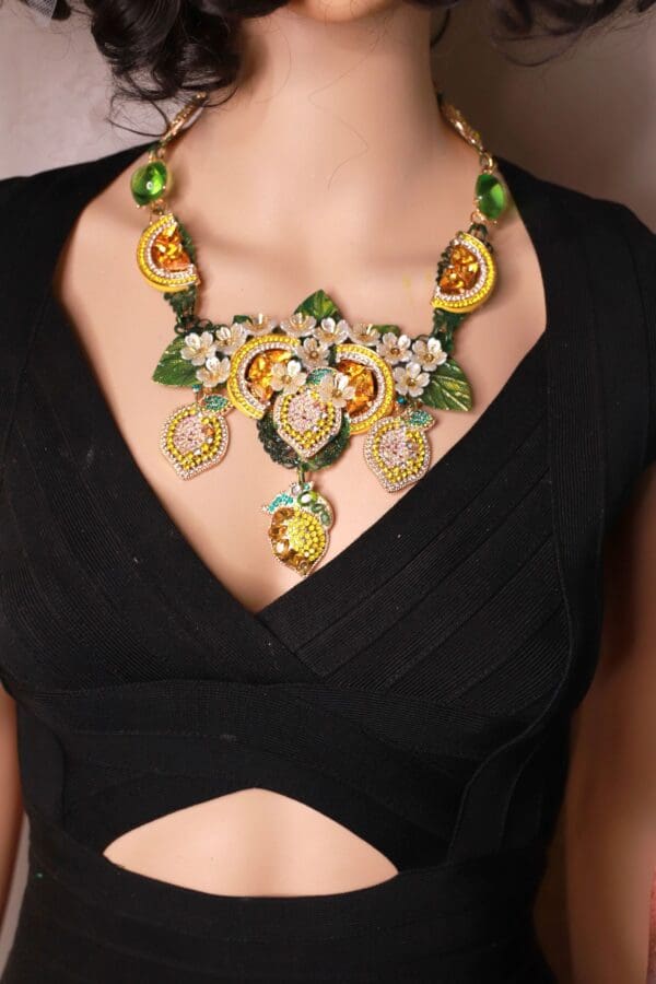 A woman wearing a necklace with green leaves and yellow flowers.