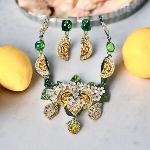 A necklace and earrings set with lemons on the table.