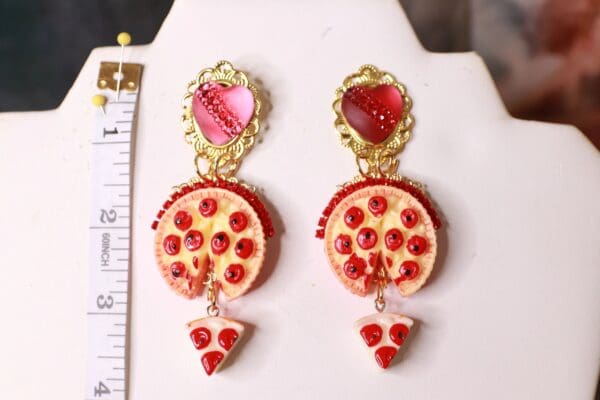 A pair of earrings with pepperoni pizza and cheese.