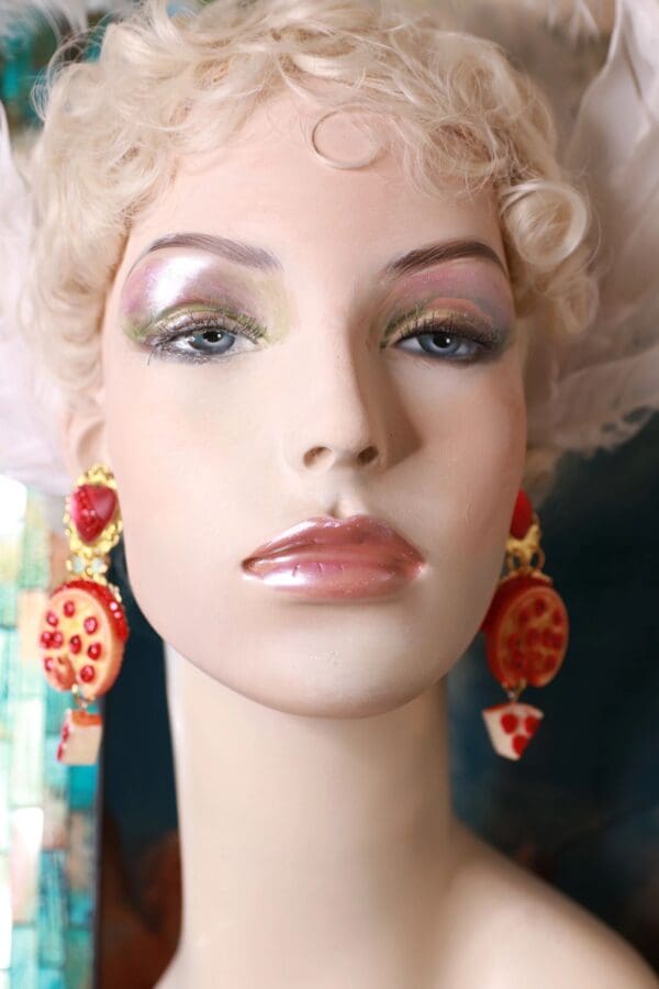 A mannequin wearing earrings with red and yellow designs.