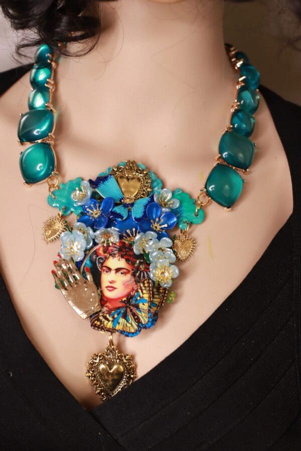 A woman wearing a necklace with blue beads and a picture of frida kahlo.