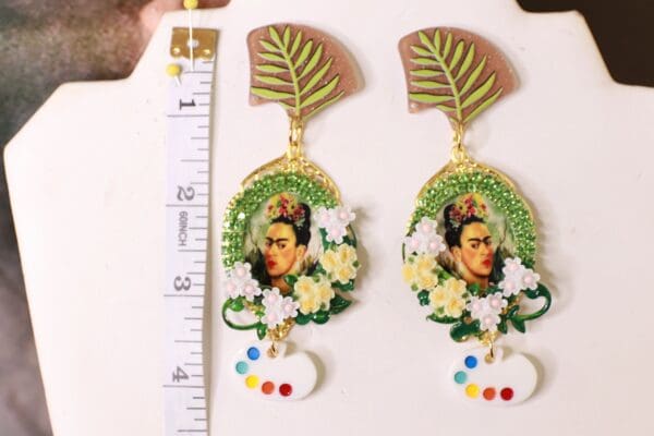 A pair of earrings with a picture and flowers.