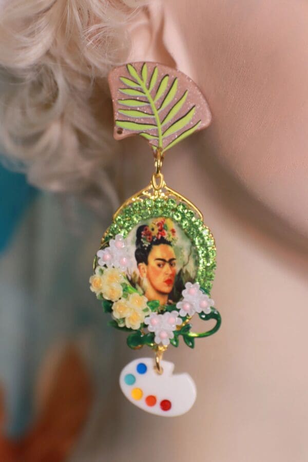 A woman wearing a green and white earring with flowers.