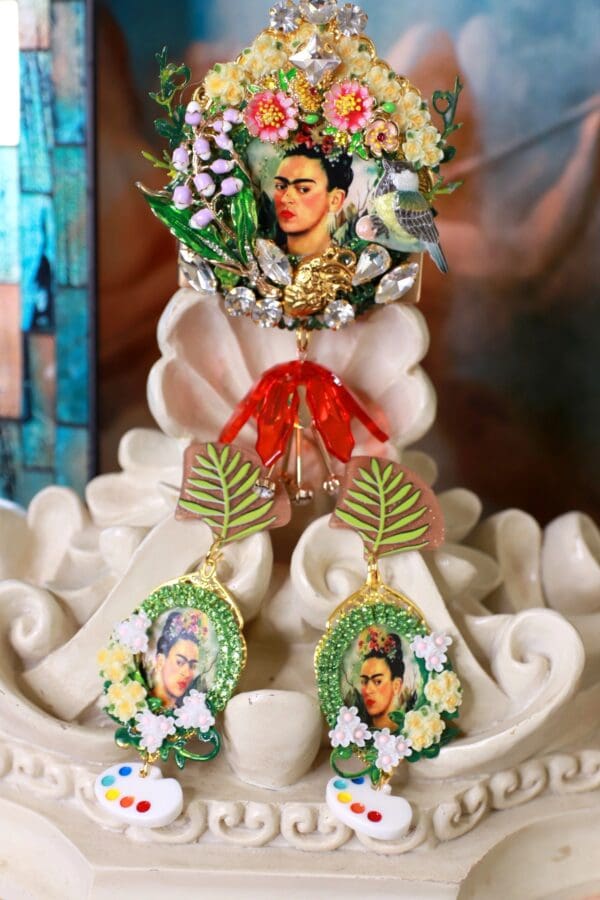 A pair of earrings with flowers and a picture of frida kahlo.