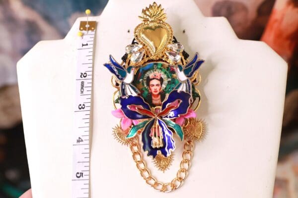 A gold chain with a large colorful necklace and a small picture of a woman.