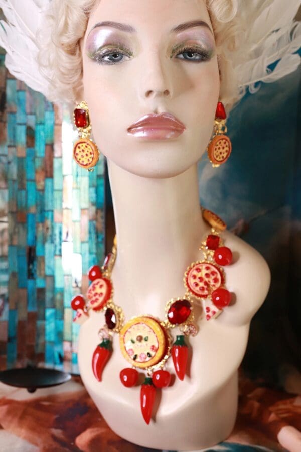 A mannequin wearing a necklace and earrings with red peppers.