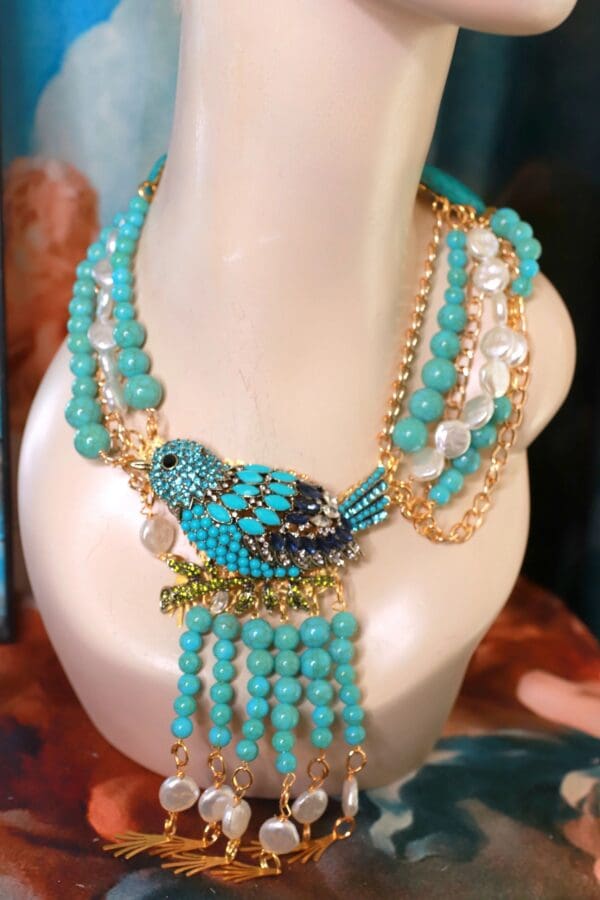 A necklace with blue beads and a bird on it.