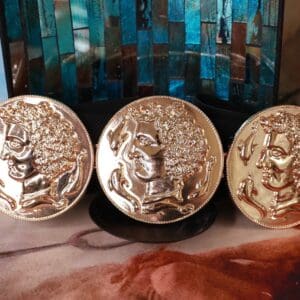 Three gold plated coins sitting on top of a table.