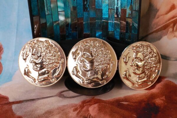 Three gold plated coins sitting on top of a table.