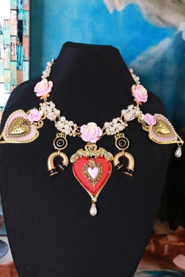 A black mannequin wearing a necklace with pink flowers.