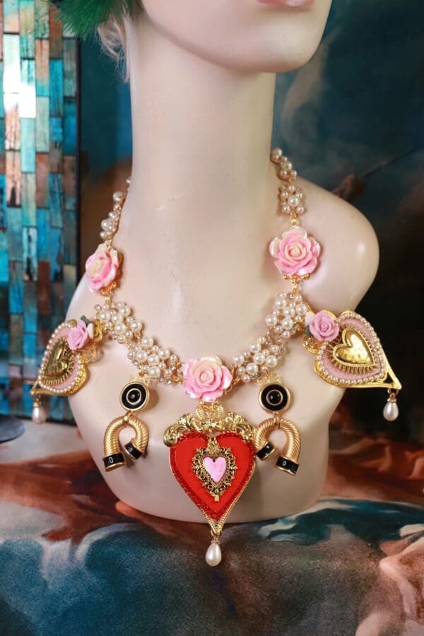 A necklace with pink roses and hearts on it.