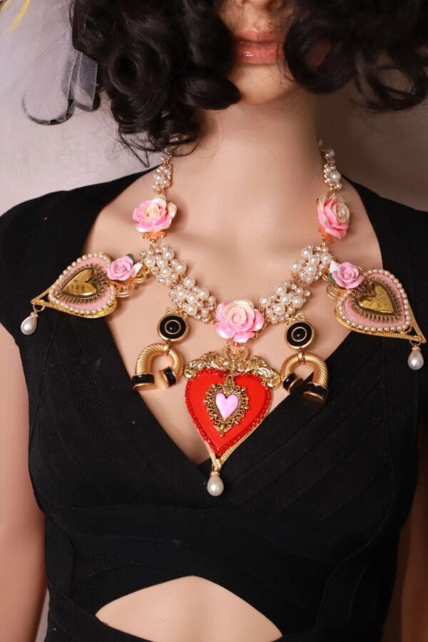 A woman wearing a necklace with hearts and flowers.