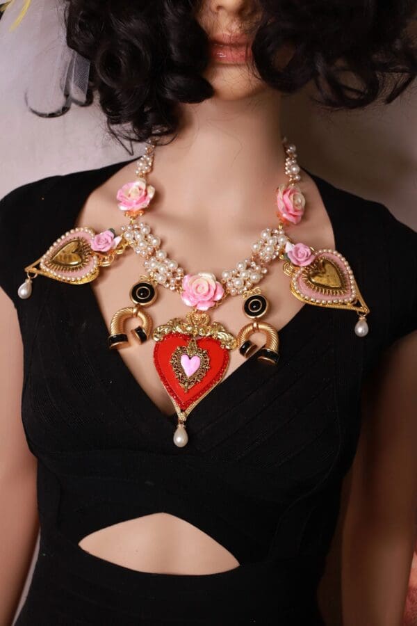 A woman wearing a necklace with hearts and flowers.