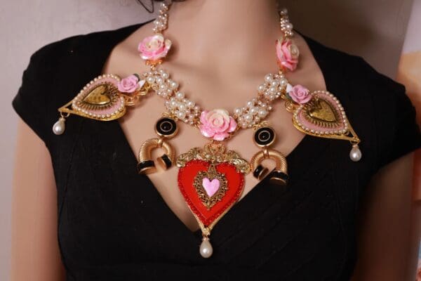A woman wearing a necklace with hearts and flowers.