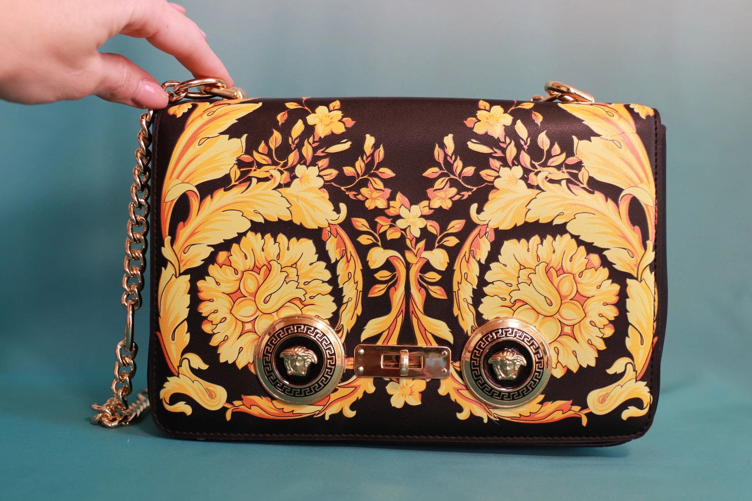 A person holding onto a purse with gold flowers on it