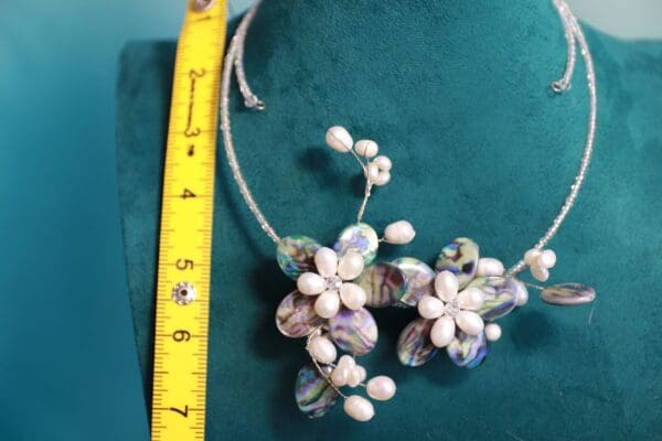 A measuring tape and some pearls on a green cloth