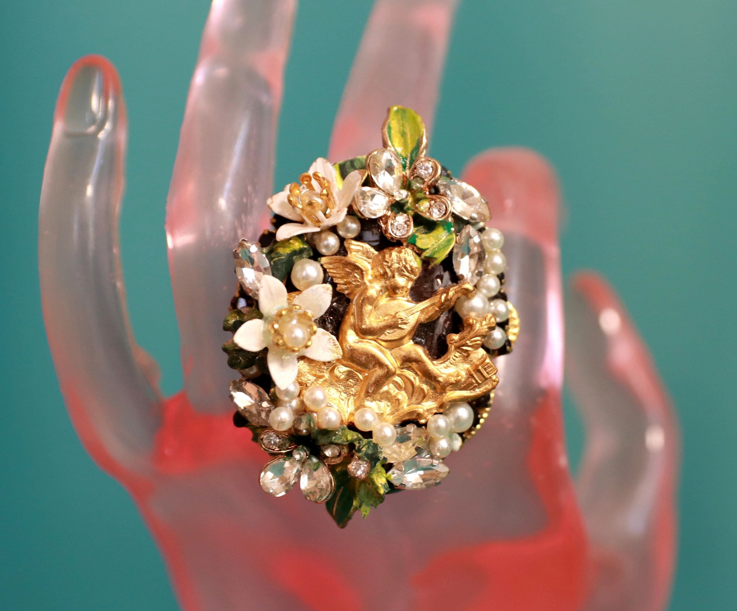 A hand holding a ring with flowers on it.