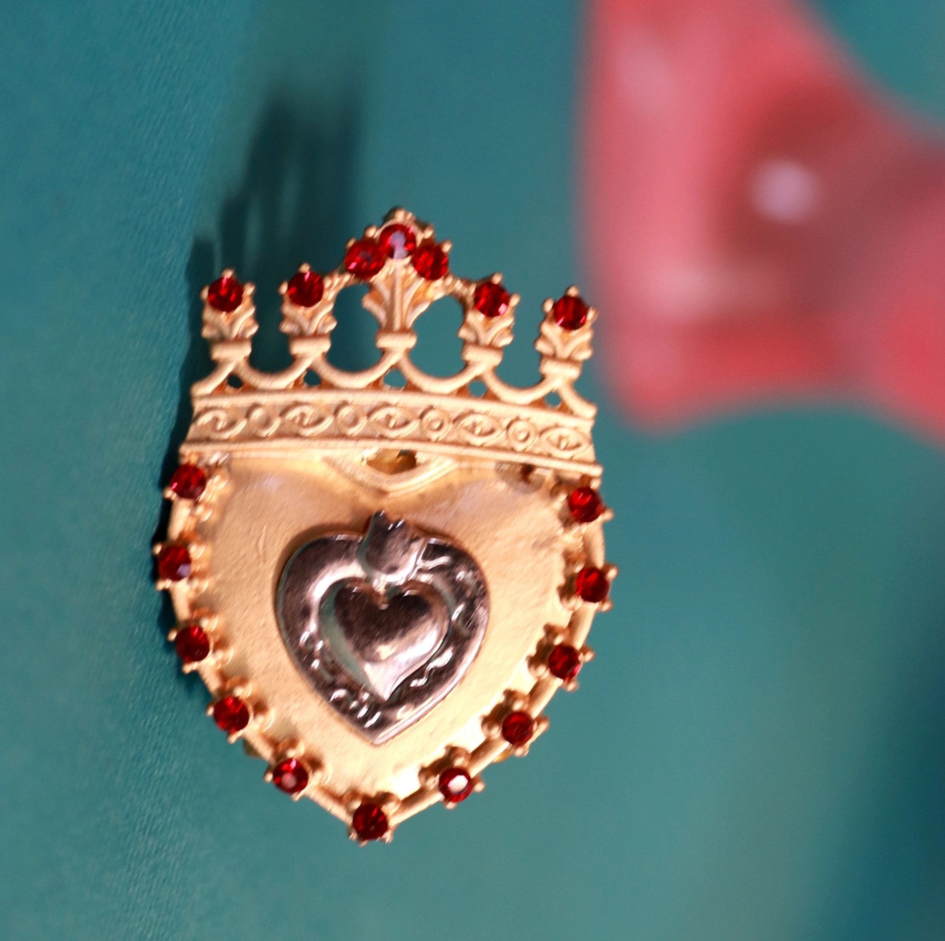 A gold and red heart shaped ornament hanging from the side of a wall.