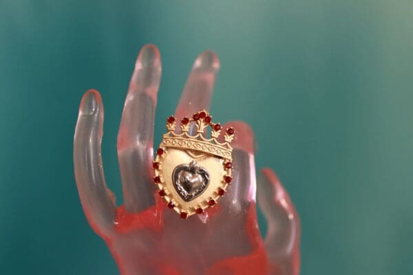 A hand with a heart shaped ring on it