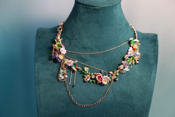A green mannequin wearing a necklace with chains and flowers.