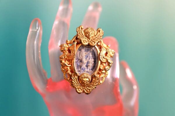 A gold ring with an ornate frame and a cat on it.
