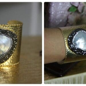 A gold bracelet with a diamond and a crystal on it.