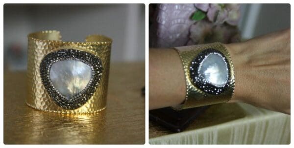 A gold bracelet with a diamond and a crystal on it.