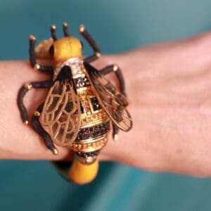 A person wearing a bracelet with a bee on it.