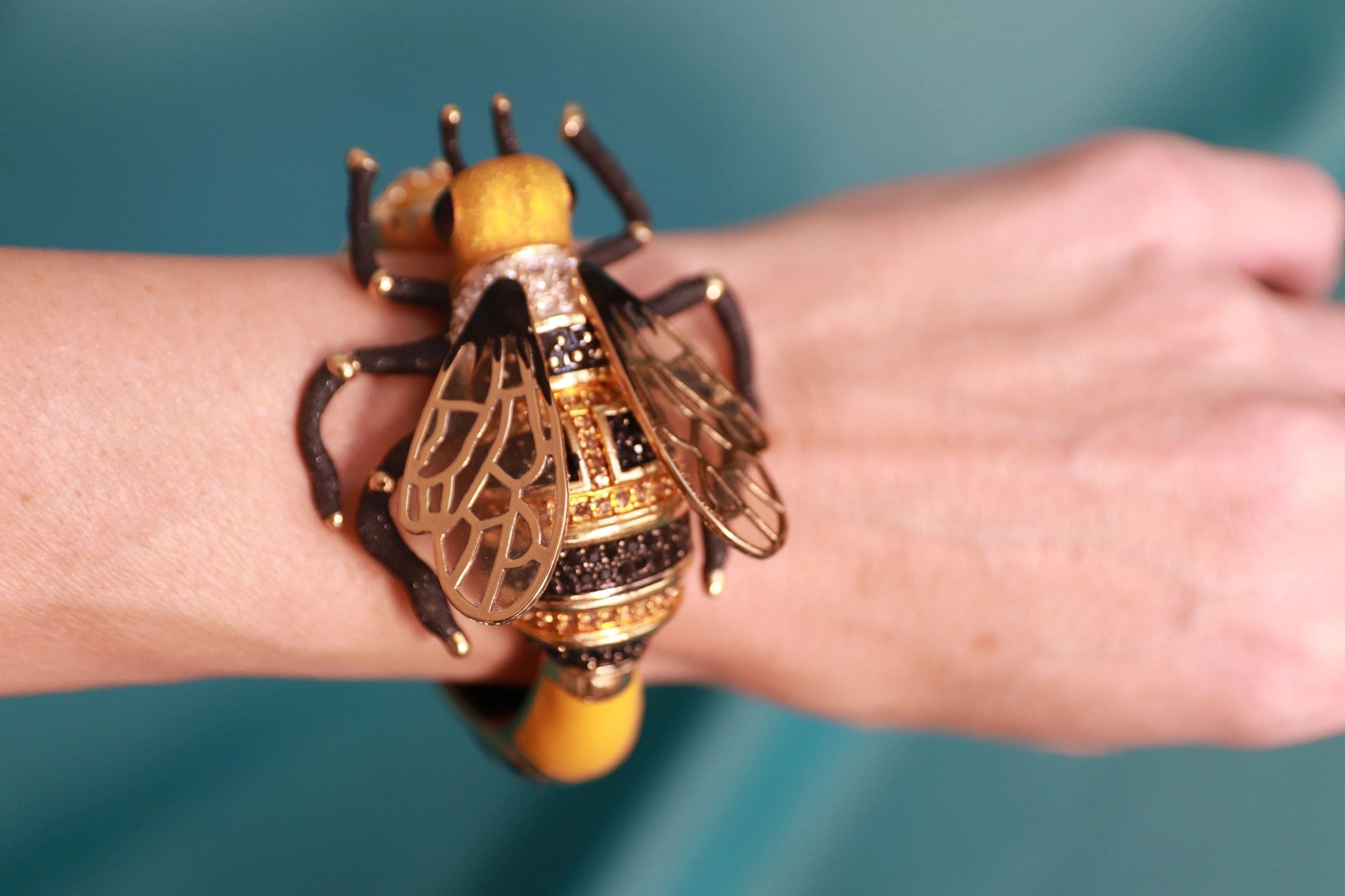A person wearing a bracelet with a bee on it.