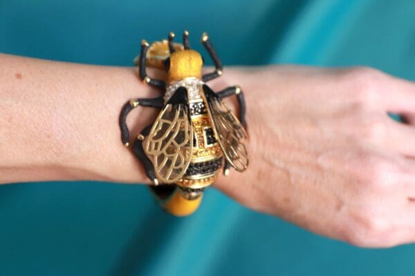 A person wearing a bracelet with a bee on it.