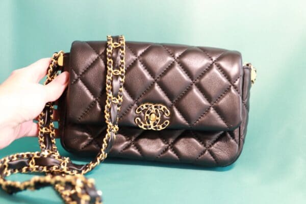 A black purse with gold chain and leopard print strap.