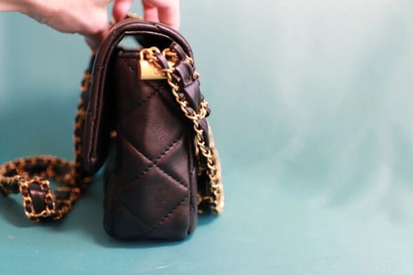 A person holding onto a purse with chain straps
