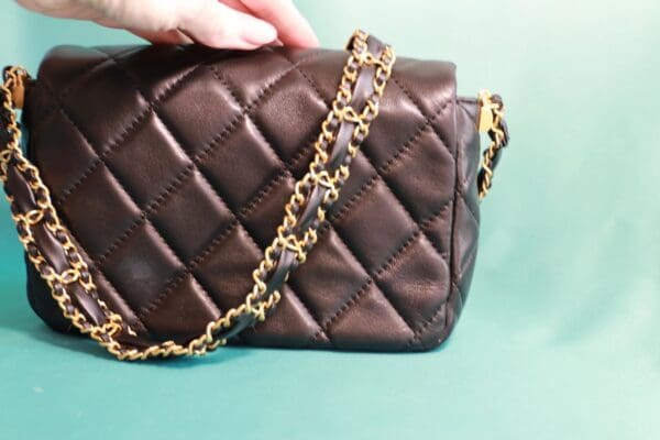 A person holding onto the chain of a purse