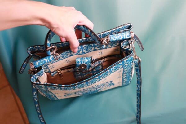 A person holding onto the handle of a purse.