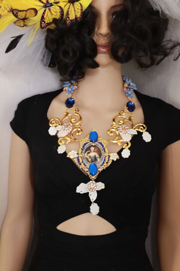 A woman wearing a necklace with blue stones and gold chains.