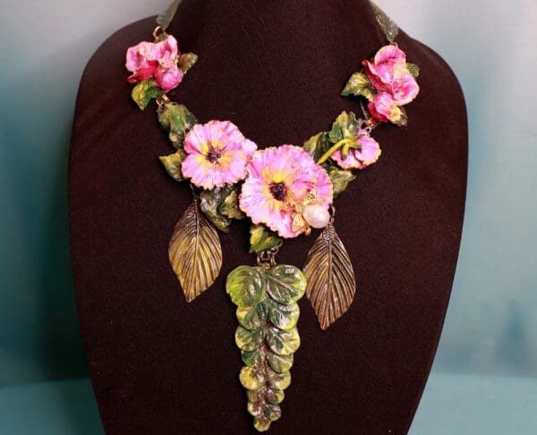 A necklace with pink flowers and leaves on it.