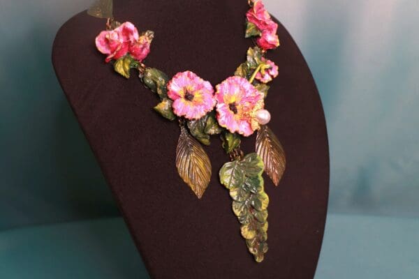 A necklace with pink flowers and leaves on it.